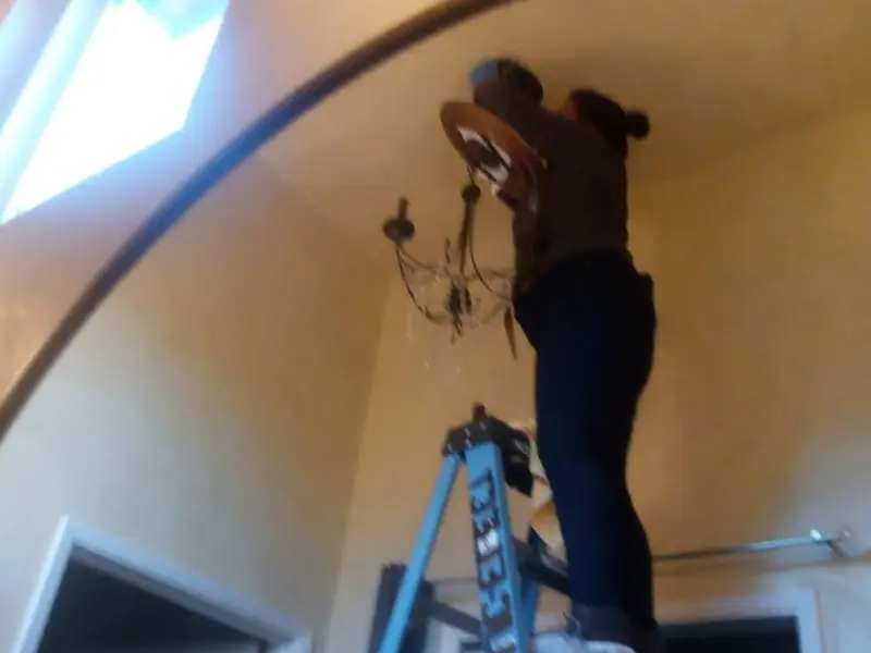 Electrician installing a chandelier in a Highland residence